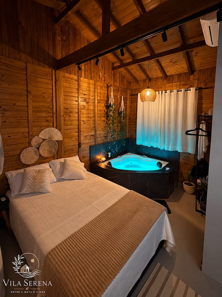 Estúdio 1: cama de casal com a banheira de hidromassagem iluminada ao fundo