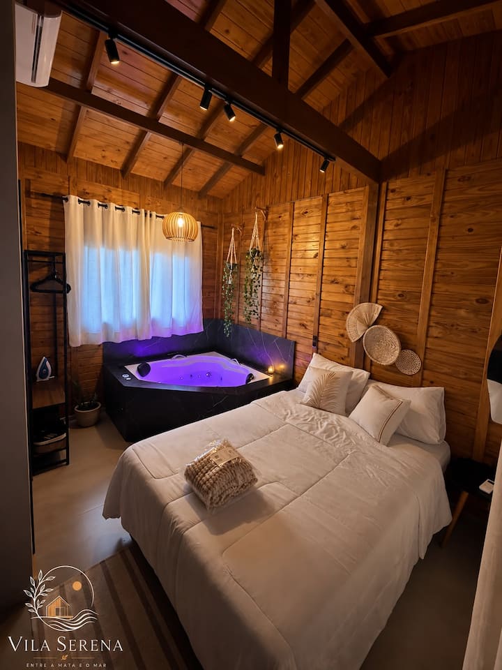Estúdio 2: quarto de madeira com a banheira acesa em roxo ao lado da cama