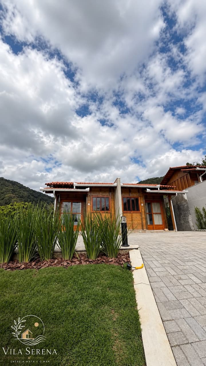 Fachada das casas de madeira da Vila, com gramado e céu azul
