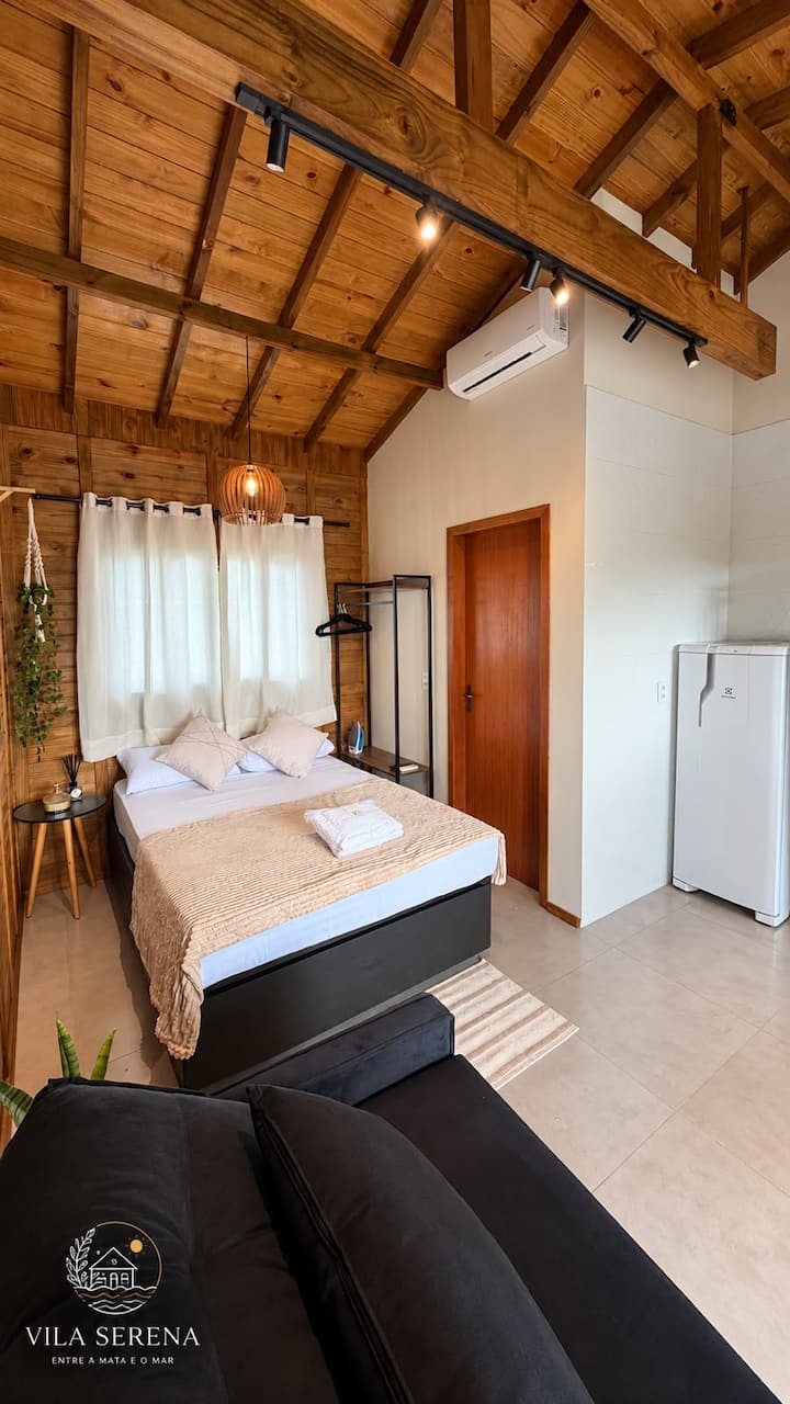 Estúdio 3: cama de casal, poltrona e cozinha no mesmo ambiente de madeira