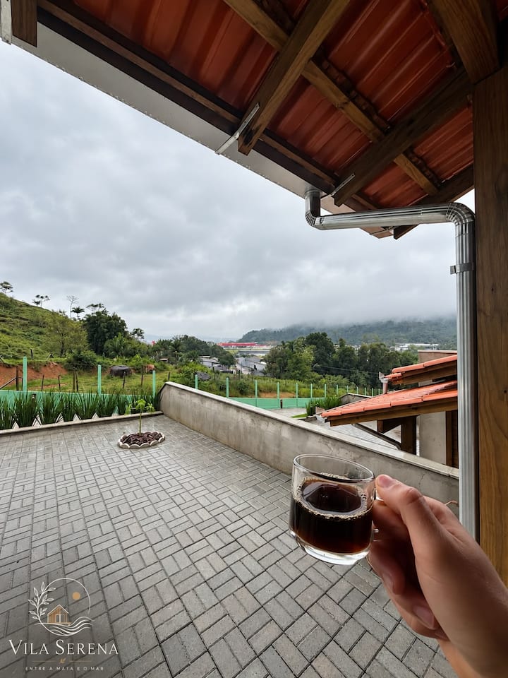 Xícara de café na varanda com vista para o vale e as casas da Vila